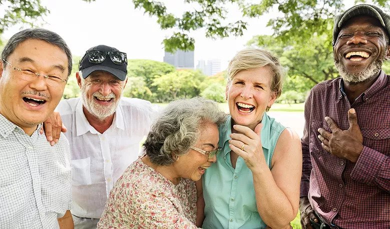 Group of five people of mixed races and genders all laughing.